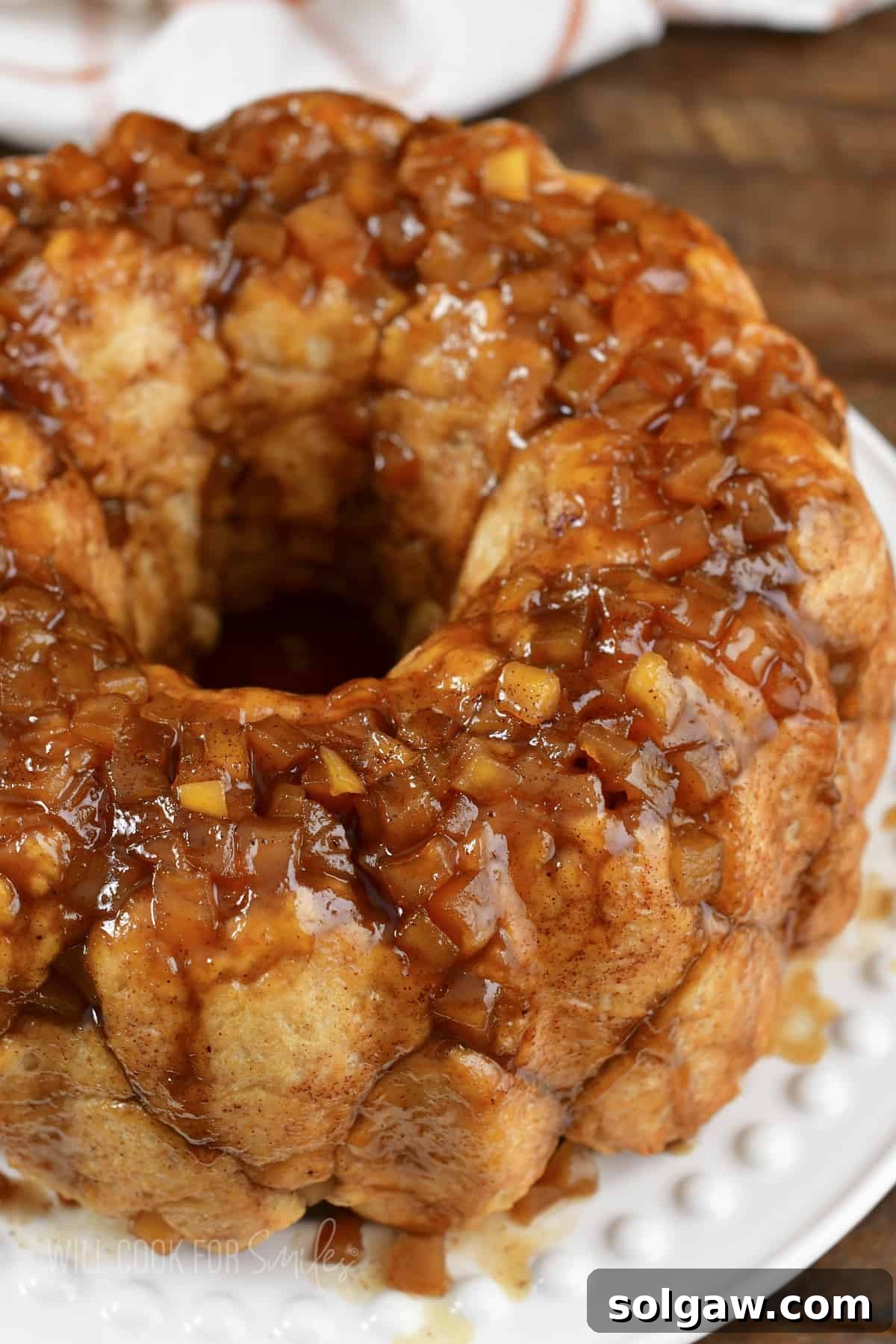 Closeup of a slice of apple monkey bread on a white dish, showing its soft interior and apple chunks.
