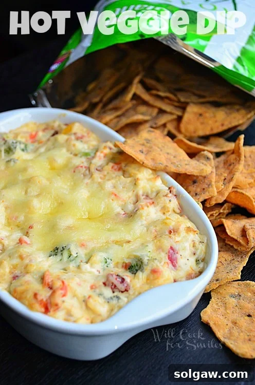 Golden Caramelized Onion Cheese Swirls 7 Hot Vegetable Dip in a casserole dish with chips to the right side, ready to be served.