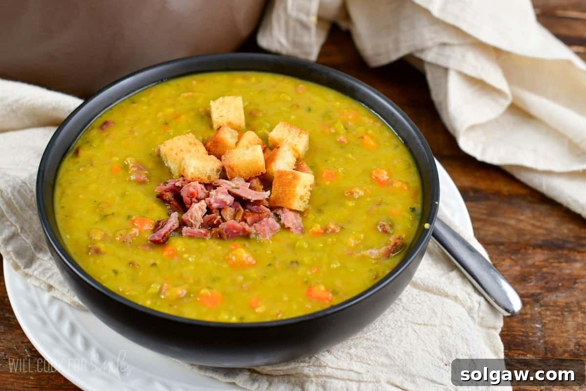 A beautifully presented bowl of split pea soup, rich and vibrant, resting on a rustic linen napkin.