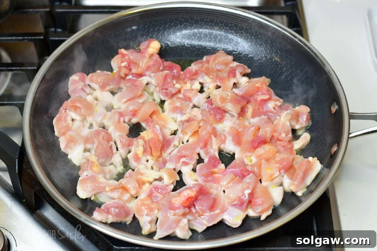 diced chicken thigh meat cooking in the pan.