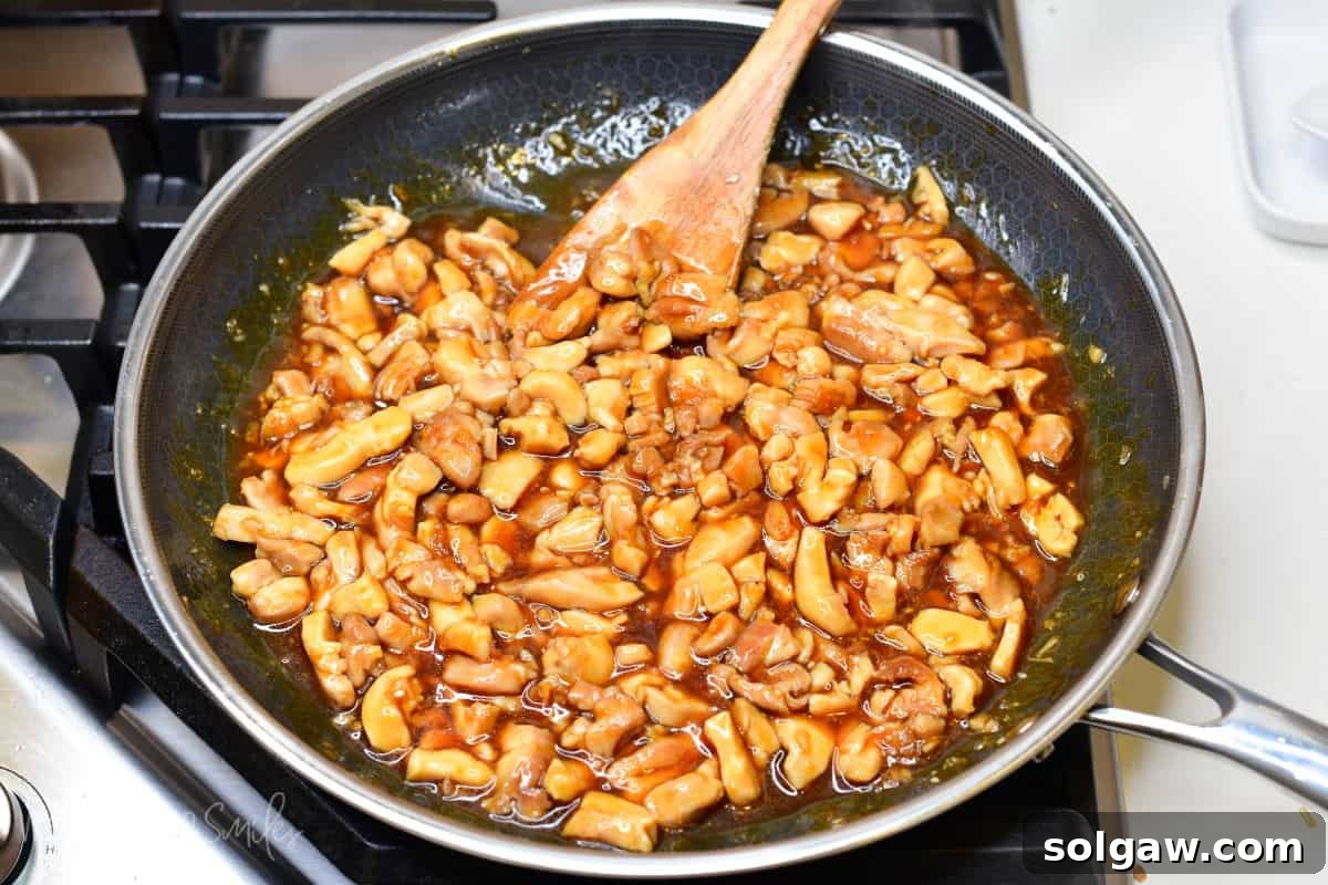 stirring cooked chicken pieces in teriyaki sauce.