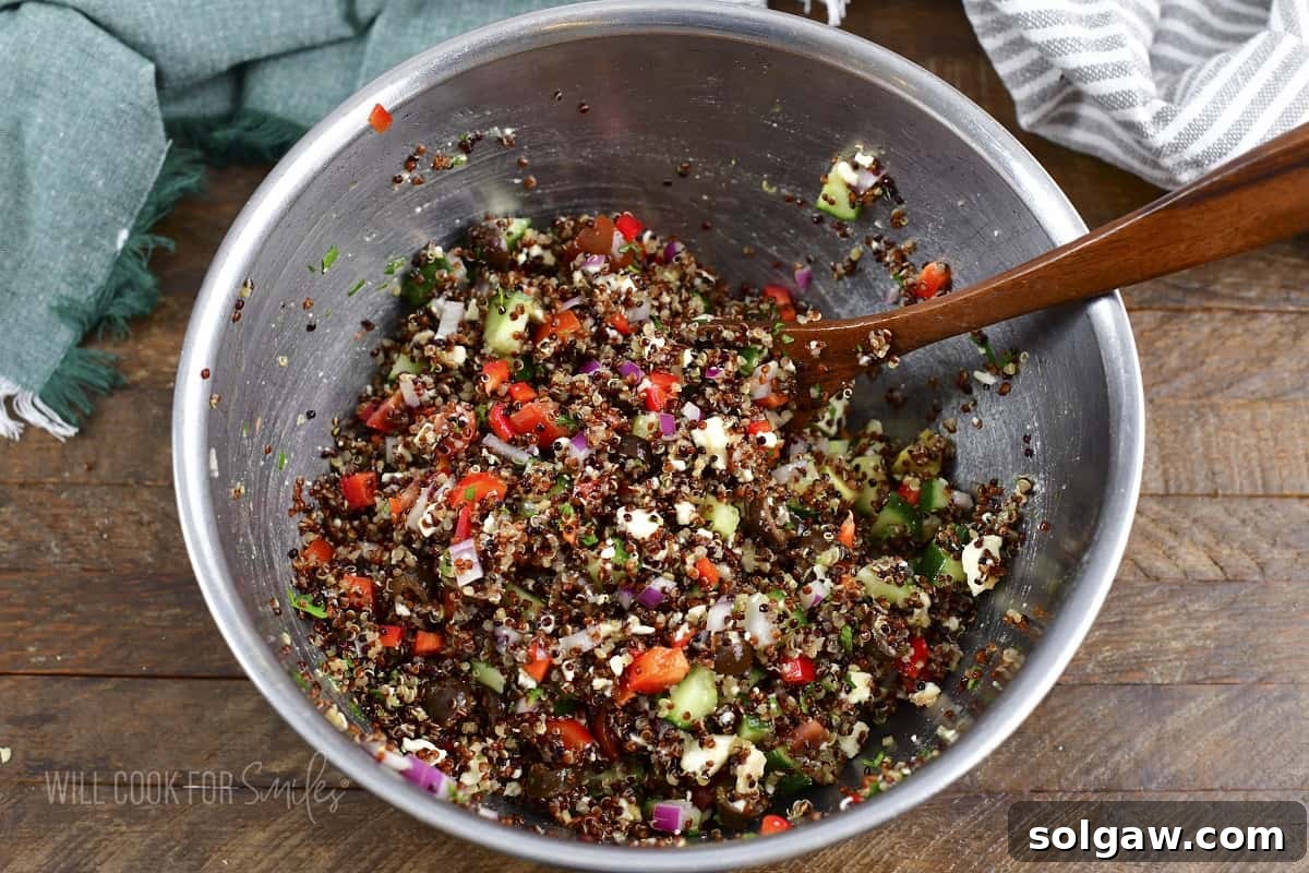 Sun-Kissed Quinoa and Feta Salad 5 mixing quinoa salad in a metal bowl.