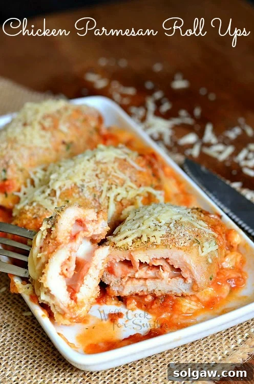 Chicken Parmesan Roll Ups on a plate, one cut in half revealing the cheesy marinara filling