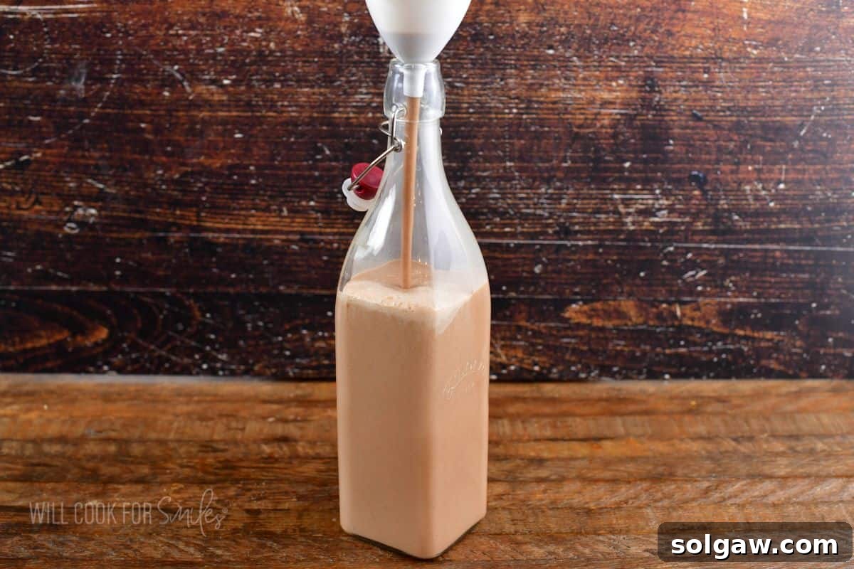pouring Irish cream into a tall bottle.