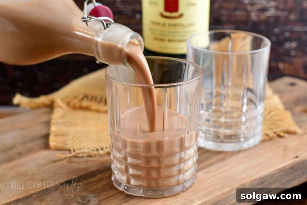 Pouring Irish cream into the glass from a bottle.