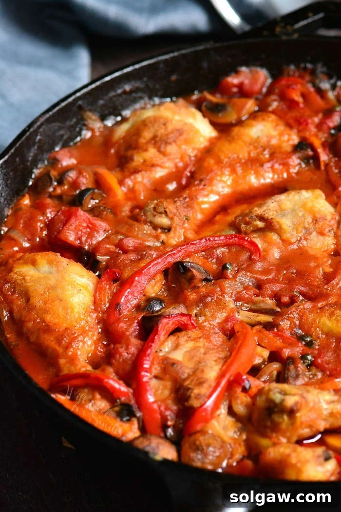 Close-up of Chicken Cacciatore cooking in a pan with rich sauce and vegetables
