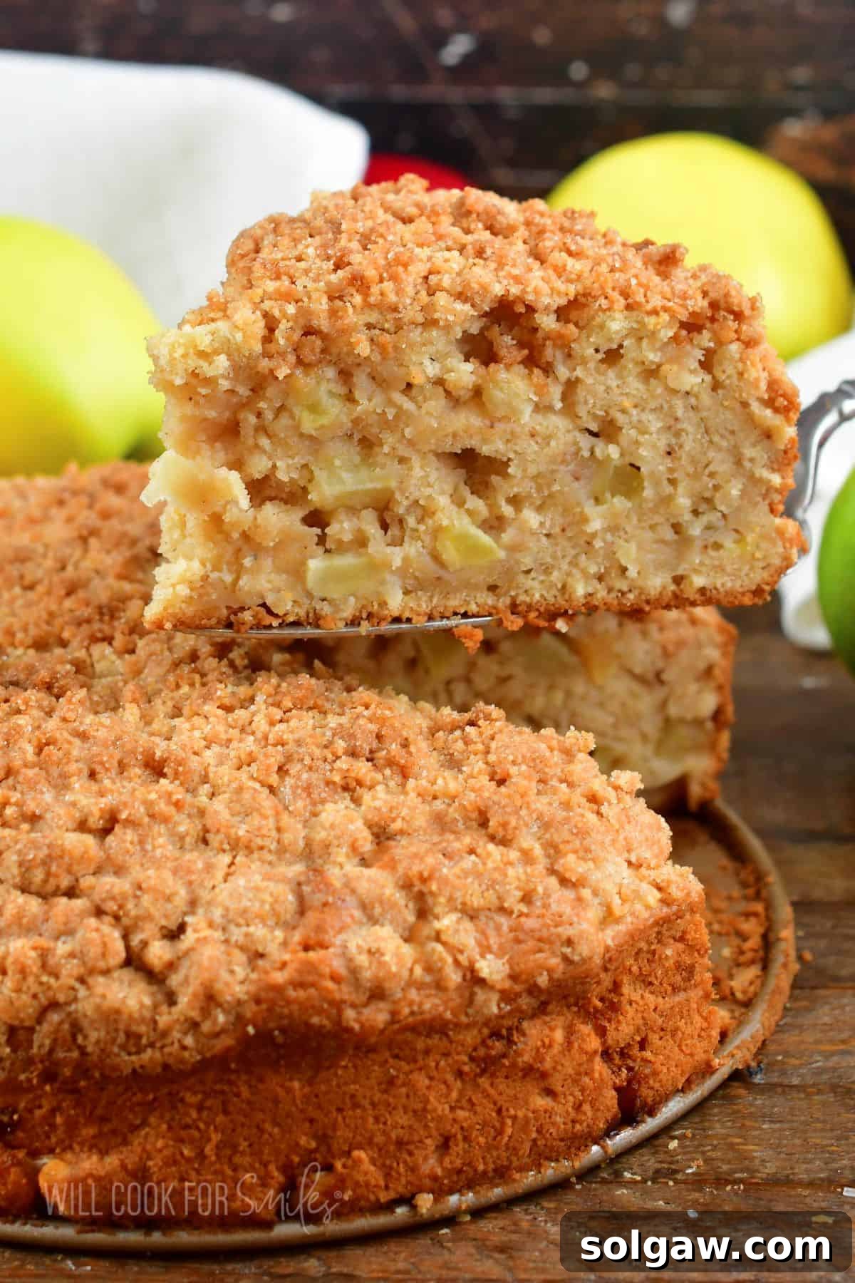 A delicious slice of Irish apple cake being carefully lifted from the main cake with a silver spatula.
