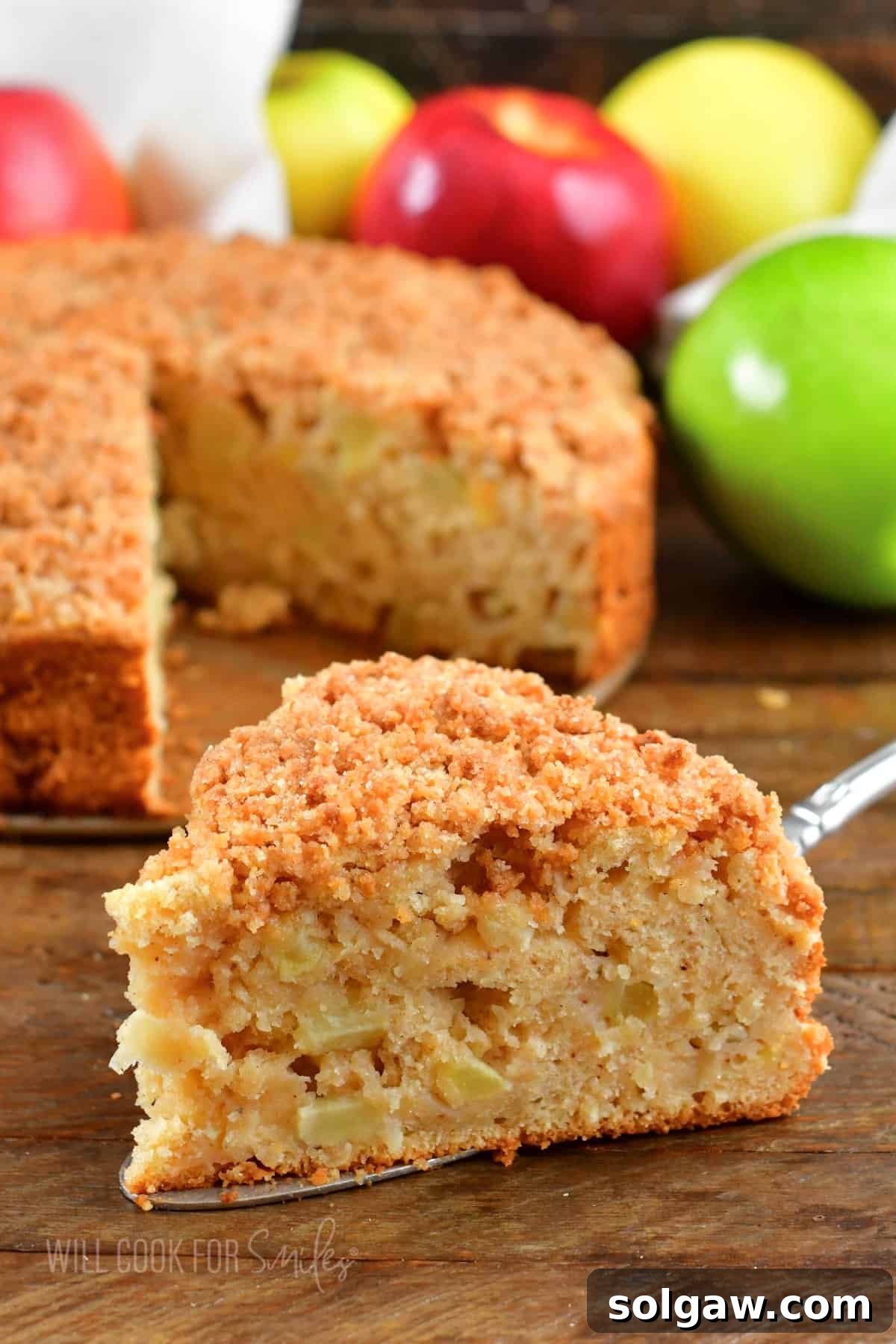 A tempting side view of a moist slice of Irish apple cake, complete with a golden streusel topping, presented on a metal spatula.