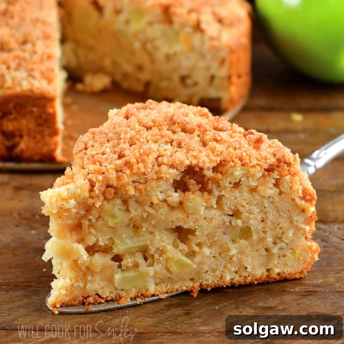 Squared view of a perfectly baked slice of Irish apple cake on a silver spatula, ready to be served.