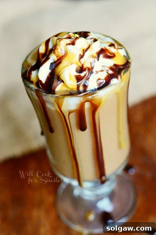 Chocolate Caramel Creamy Frozen Coffee in a glass cup with whip cream and chocolate sauce on top, garnished with chocolate shavings