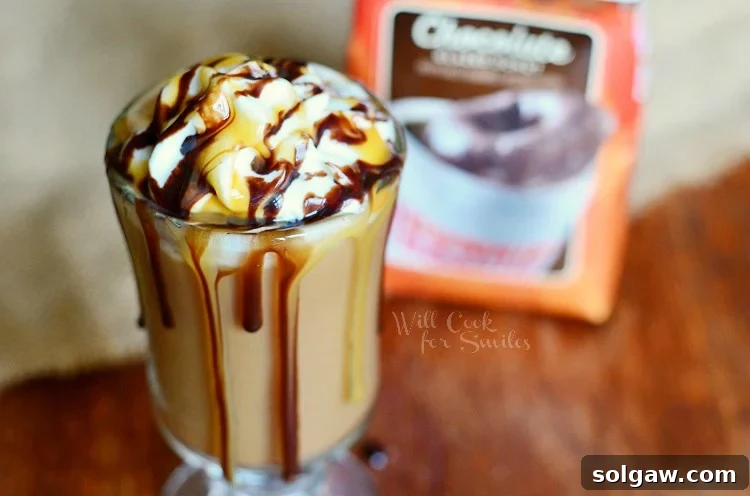 Close-up of a glass cup filled with Chocolate Caramel Creamy Frozen Coffee, topped with whipped cream and caramel drizzle