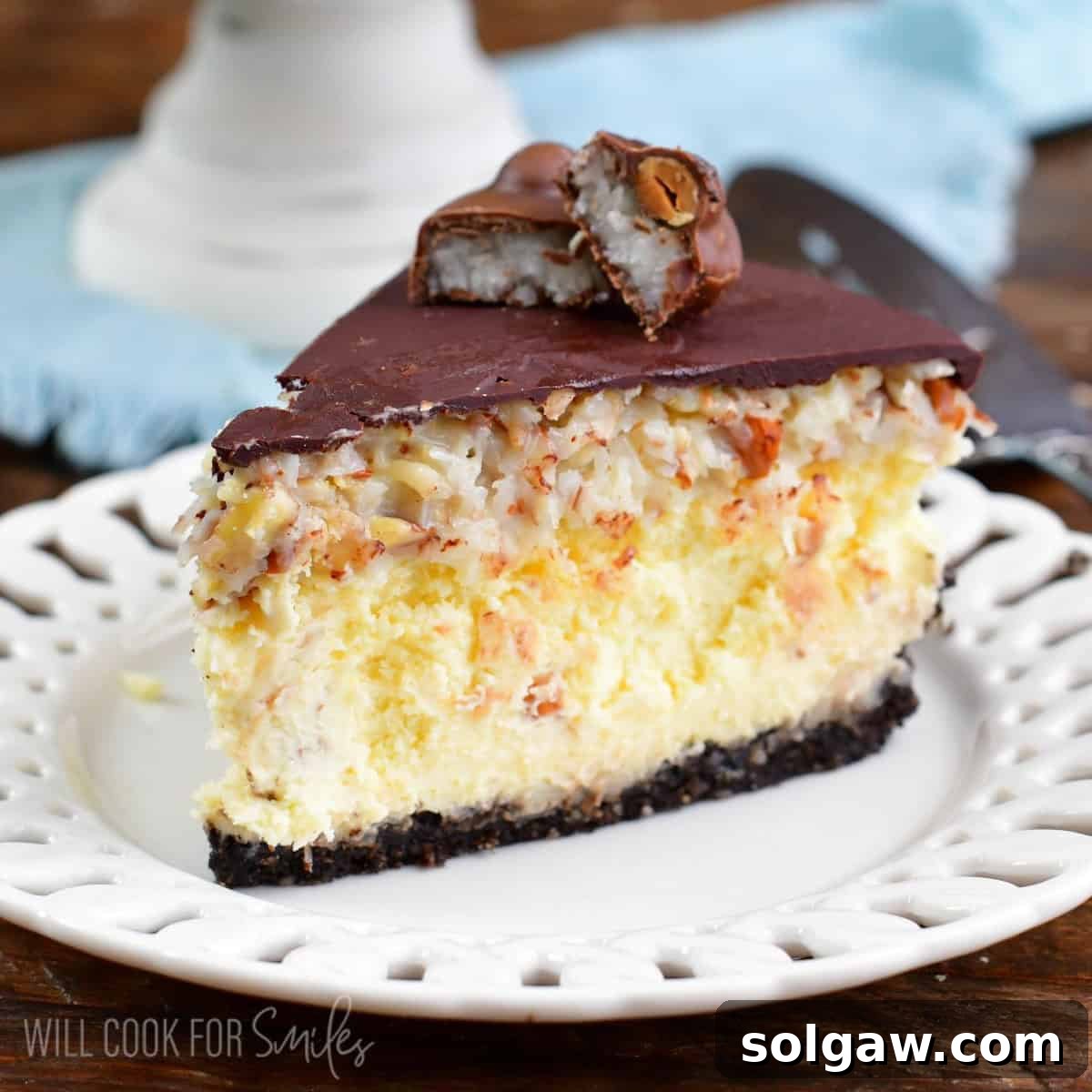 A slice of Almond Joy cheesecake on a white plate, ready to be enjoyed.