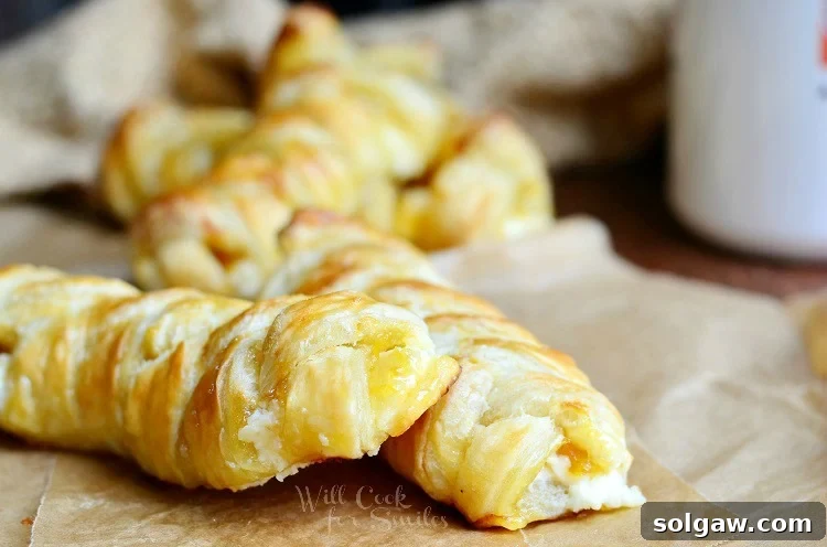 Close-up of easy braided breakfast pastries on parchment paper, showcasing their golden-brown crust.