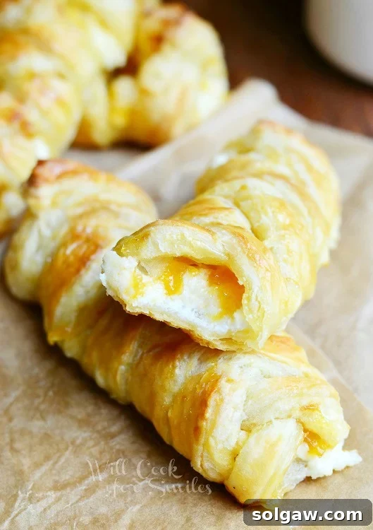 Close-up of a braided breakfast pastry with a bite taken, revealing the peach jam and cream cheese filling.