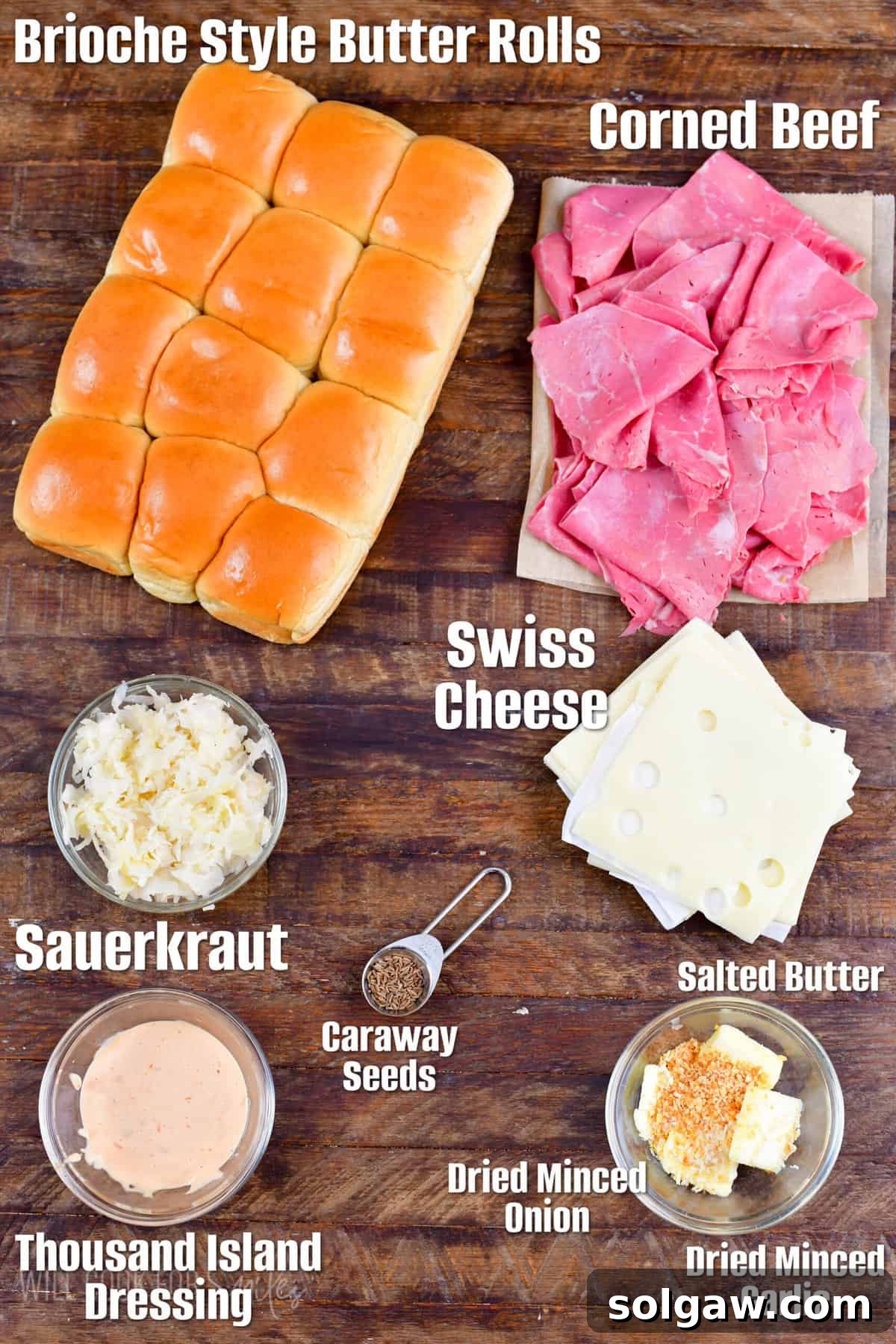 Labeled ingredients for Reuben sliders including rolls, corned beef, Swiss cheese, sauerkraut, Thousand Island dressing, and seasonings on a rustic wood surface.
