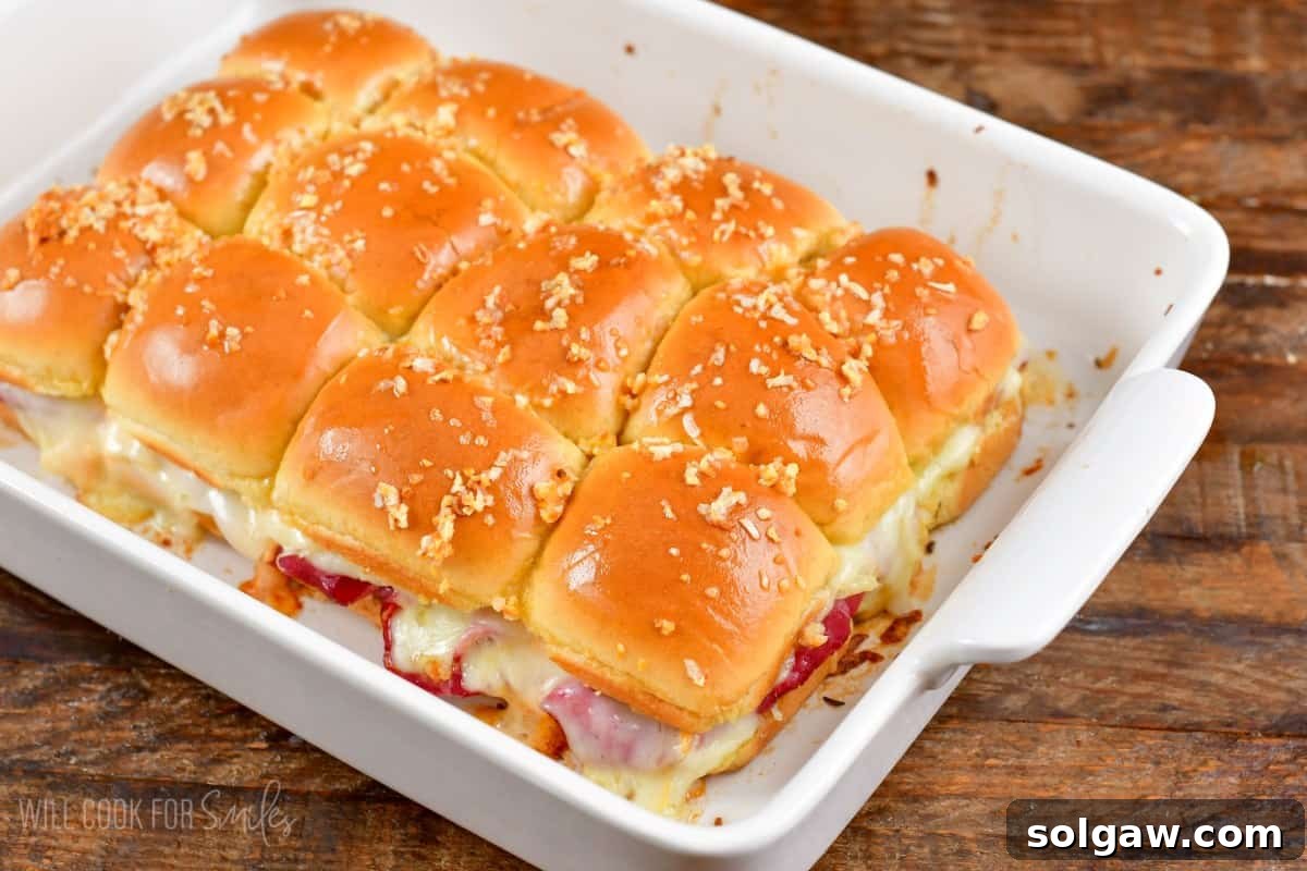 Freshly baked Reuben sliders in a baking dish, served on a wooden surface.