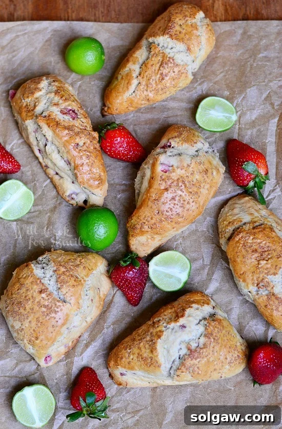 Sun-Kissed Strawberry Scones 5 Overhead close-up shot of baked Strawberry Key Lime Scones on butcher paper, showcasing their perfect golden crust and the vibrant colors of fresh strawberries and key limes