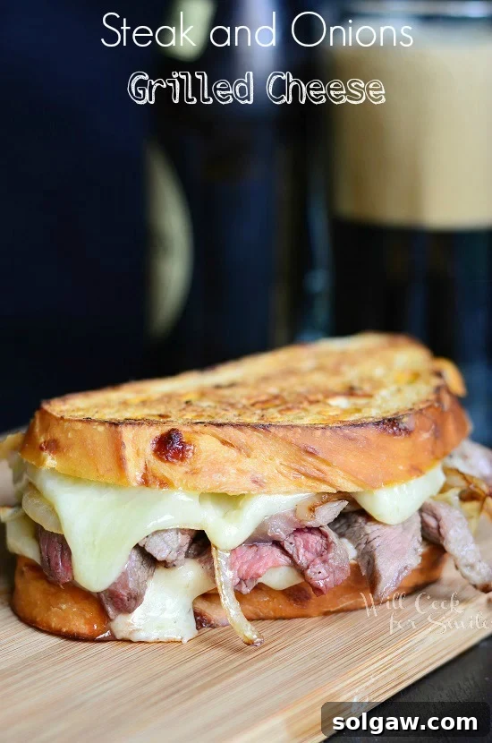 A perfectly golden-brown Steak and Caramelized Onion Grilled Cheese sandwich, sliced in half, revealing melted cheese, tender steak, and sweet onions, resting on a rustic cutting board.