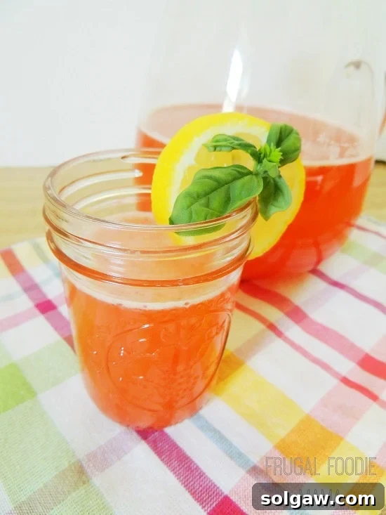 strawberry lemonade in a mason jar with lemon and basil on the rim 