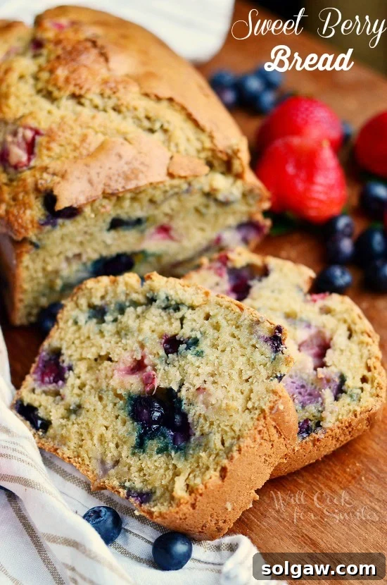 berry bread slices on a wood table with strawberry and blueberries in the background