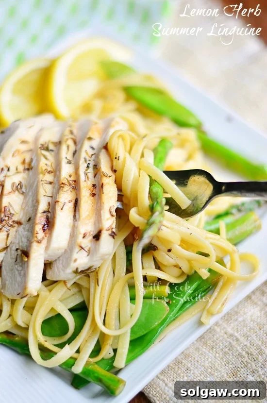 Linguine with Chicken, Asparagus and Snow Peas on a white square plate, garnished with lemon slices and served with a fork.