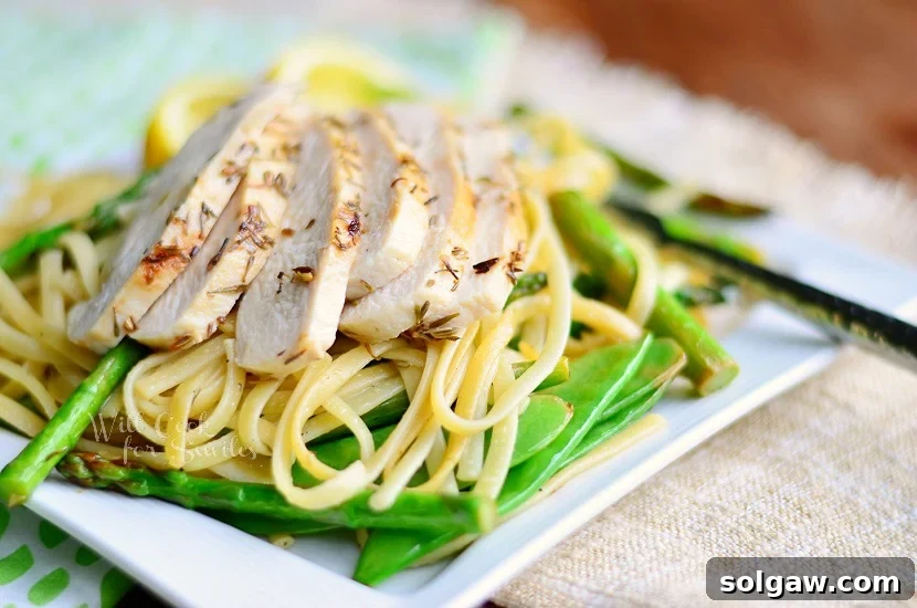 Close-up shot of Lemon Herb Linguine with Chicken, Asparagus and Snow Peas on a white square plate.