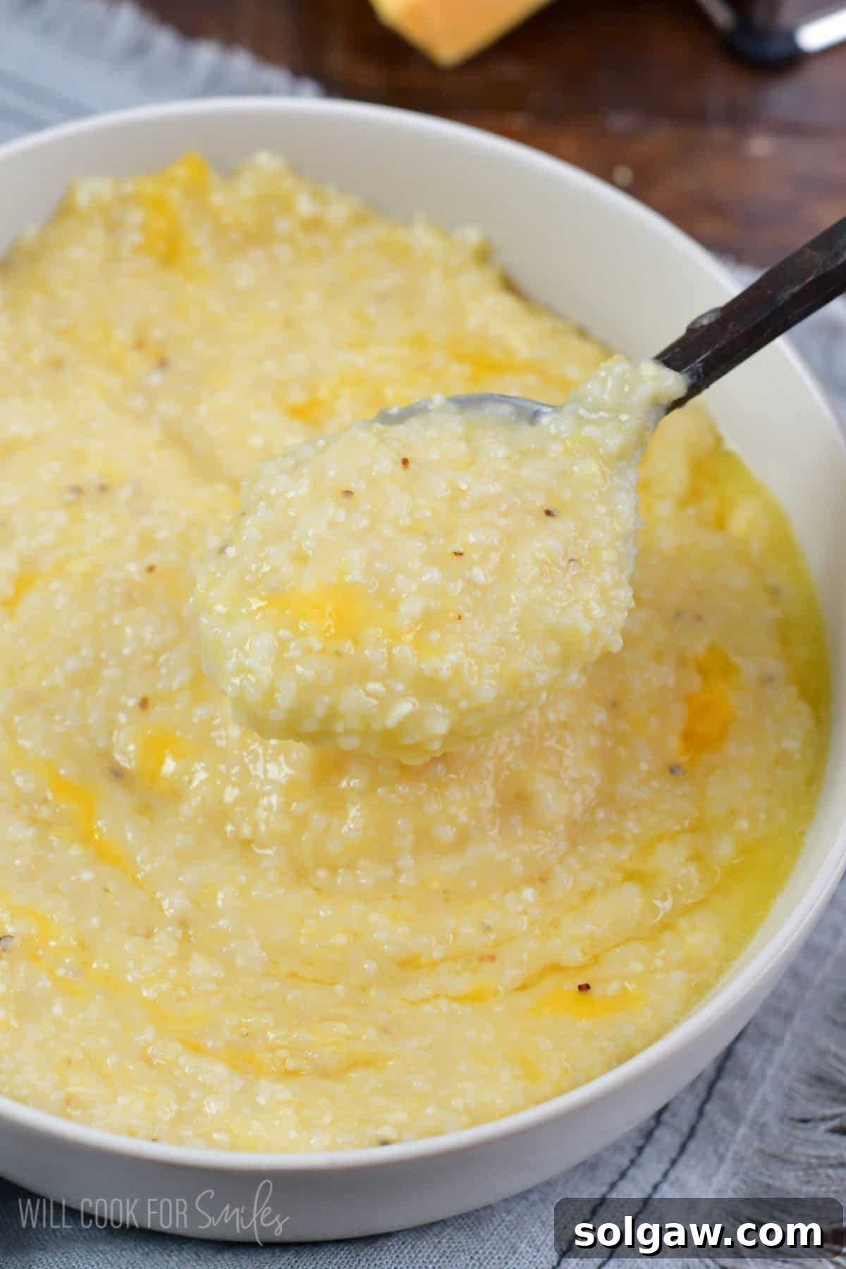 A spoon lifting creamy cheesy grits from a bowl, ready to be enjoyed.