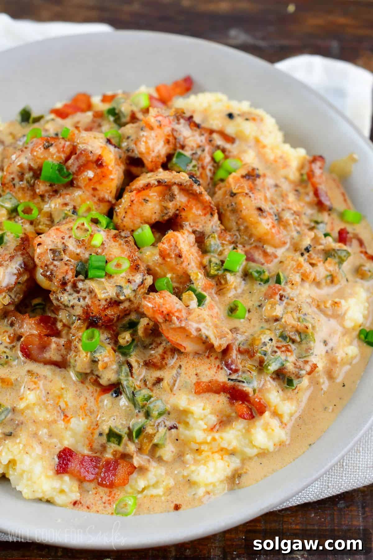 creamy Cajun shrimp and grits in a grey bowl topped with green onion.