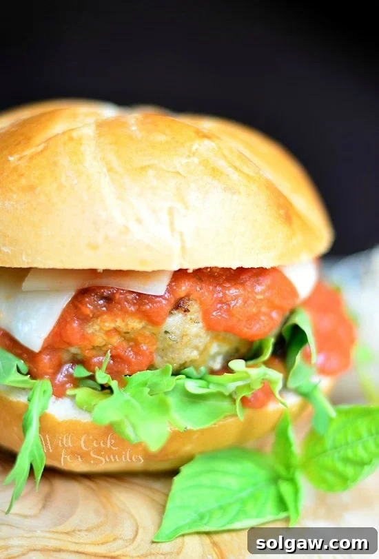 Chicken Parmesan Burger with fresh basil on the bun on a rustic wood cutting board, ready to be served