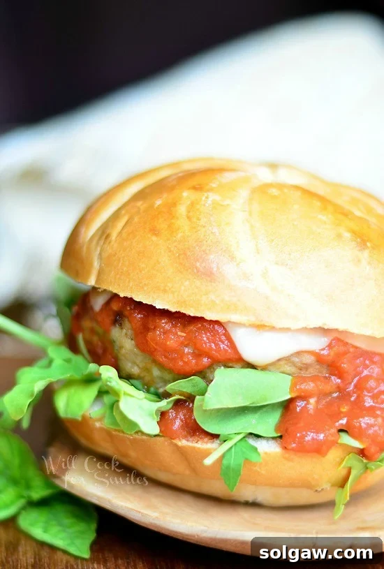 Chicken Parmesan Burger with fresh basil on the bun on a wood cutting board, showcasing a different angle and vibrant colors