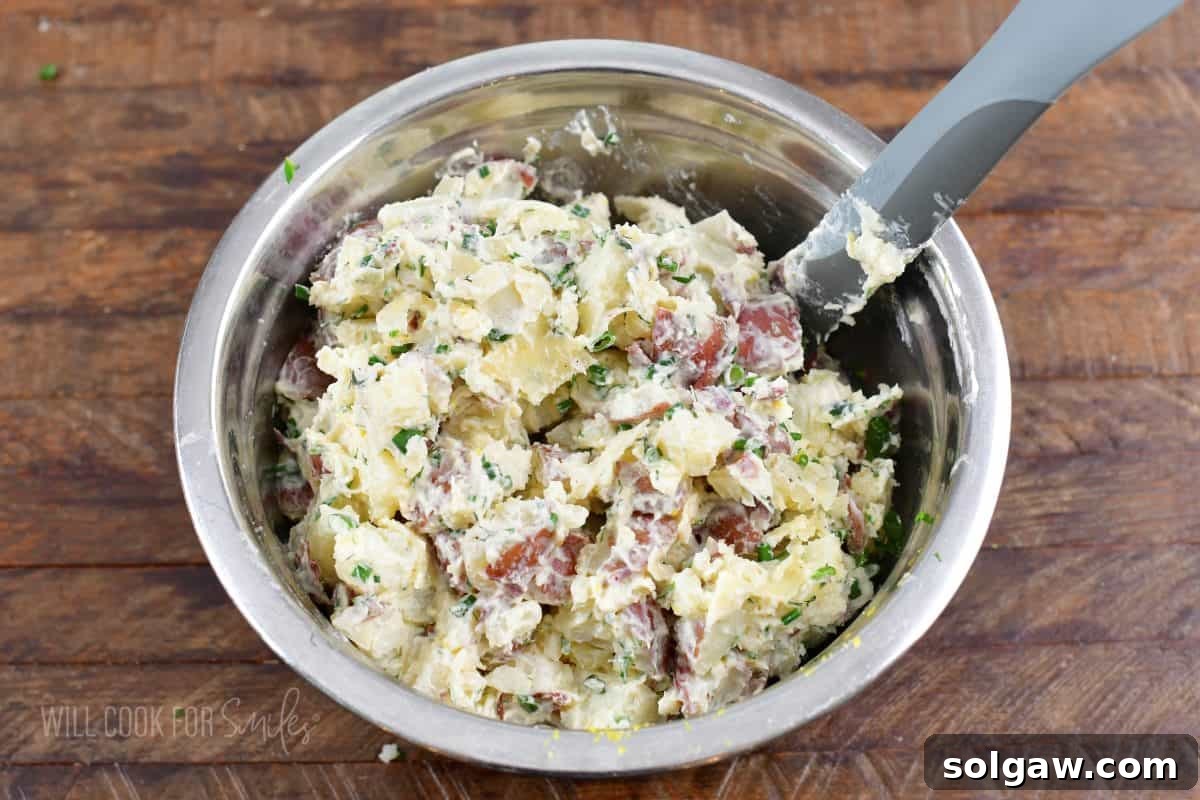 mixed parmesan potato salad in a mixing bowl with a spatula.