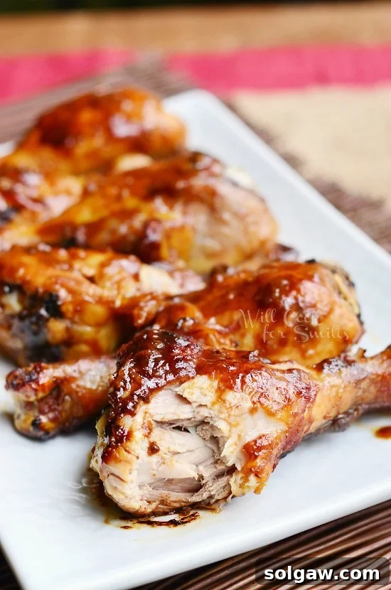 A perfectly roasted Asian Chicken Drumstick with a bite taken out, revealing the succulent meat inside. Garnished with fresh green onions.