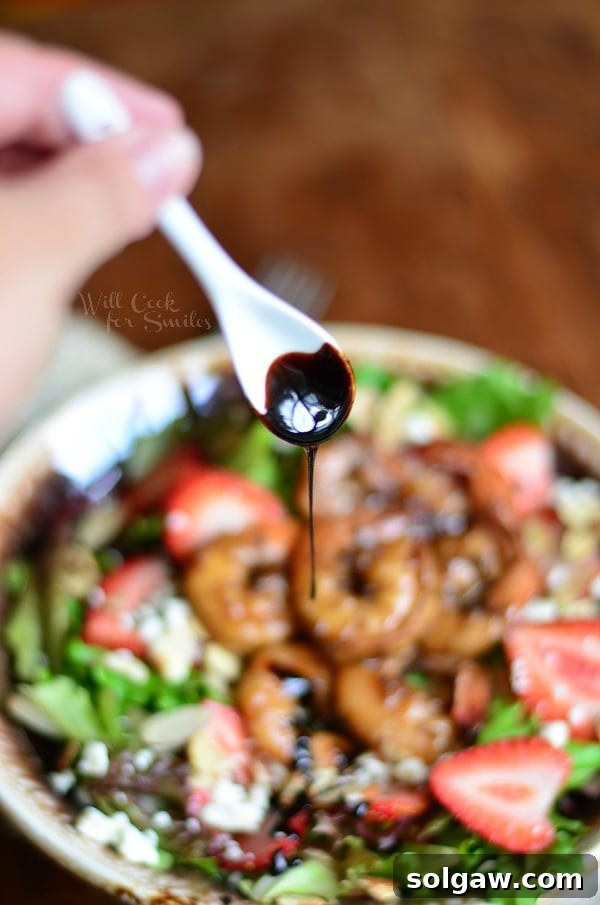 drizzling balsamic reduction over salad with a small white spoon 