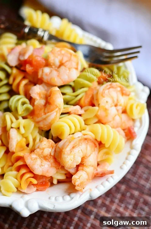 Chipotle Shrimp Bacon & Tomato Pasta in a white bowl with a fork 