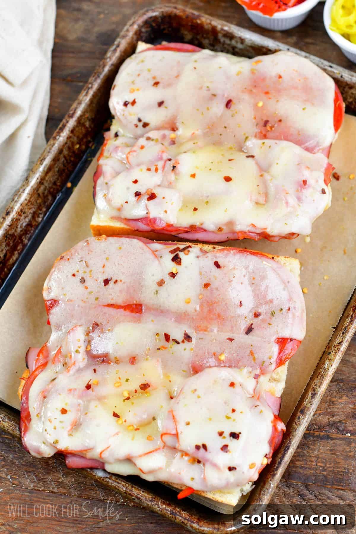 An open baked Italian sub, revealing perfectly melted cheese and warm, savory meats after being taken out of the oven.