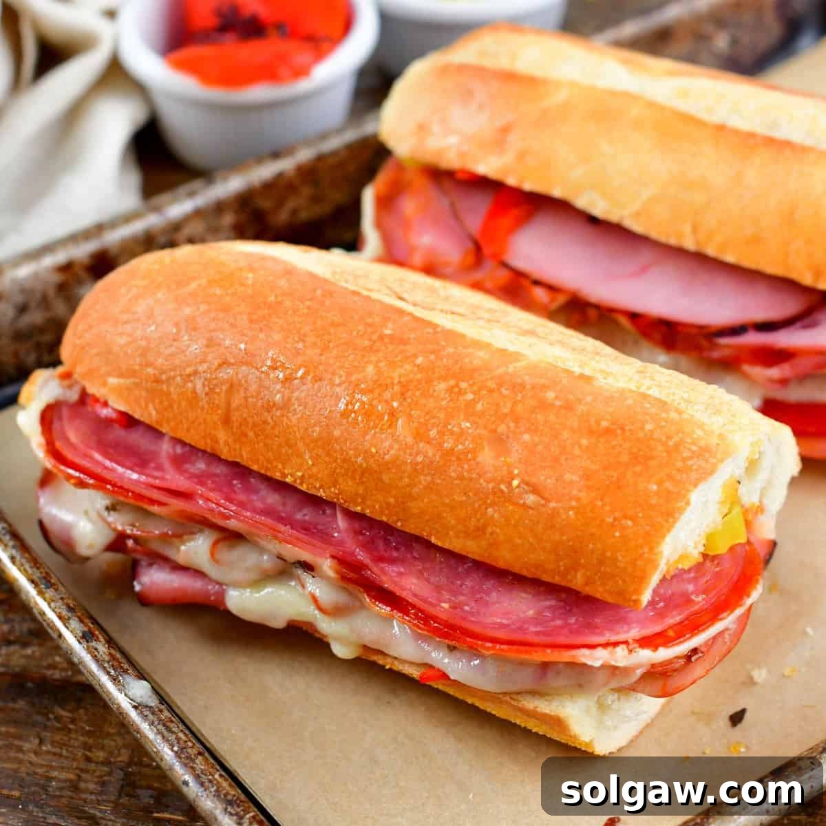 A delicious baked Italian sub sandwich cut in half on a baking sheet, ready to eat.