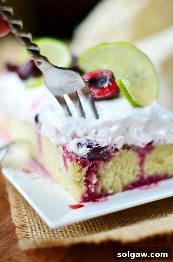 Cherry Limeade Poke Cake on a plate with a fork poking in the cake