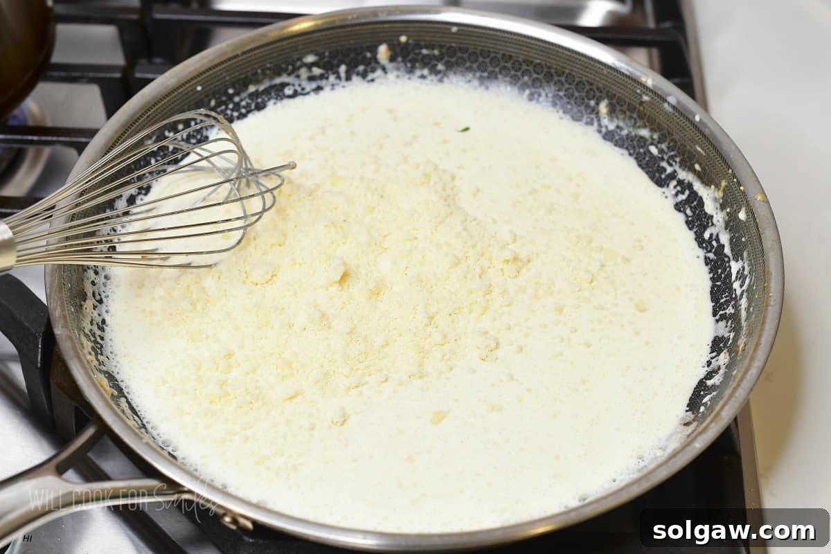 adding grated parmesan to cream sauce.