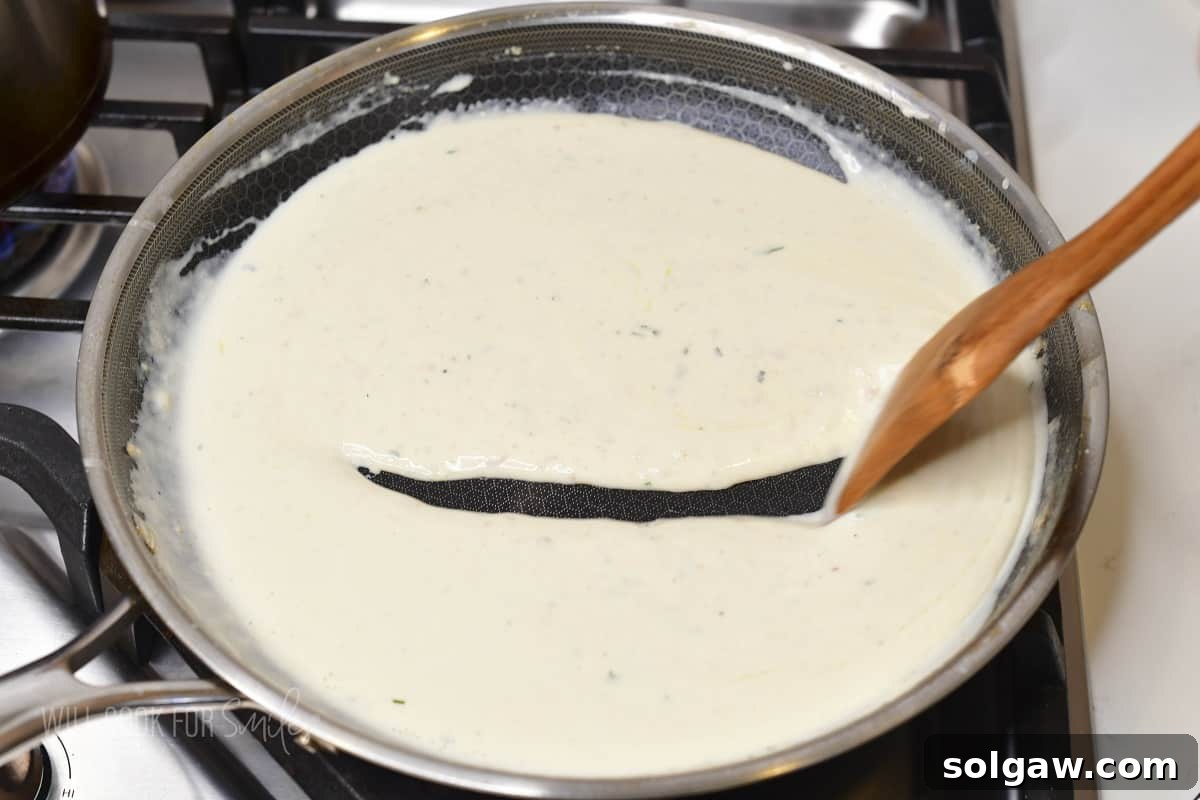 stirring parmesan cream sauce in the pan.