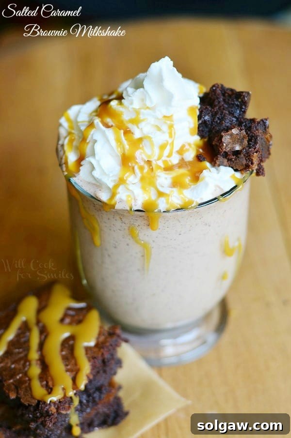 Salted Caramel Brownie Milkshake in a tall glass with whipped cream and caramel drizzle on top, garnished with a brownie piece.