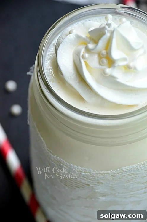 White Wedding Cake Milkshake in a mason jar with whipped cream on top and candy pearls