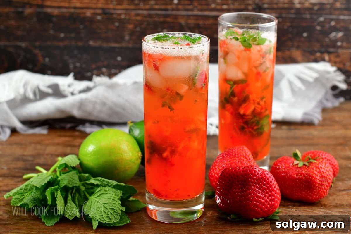 A cocktail shaker filled with muddled strawberries, mint, lime, and rum, ready to be poured.