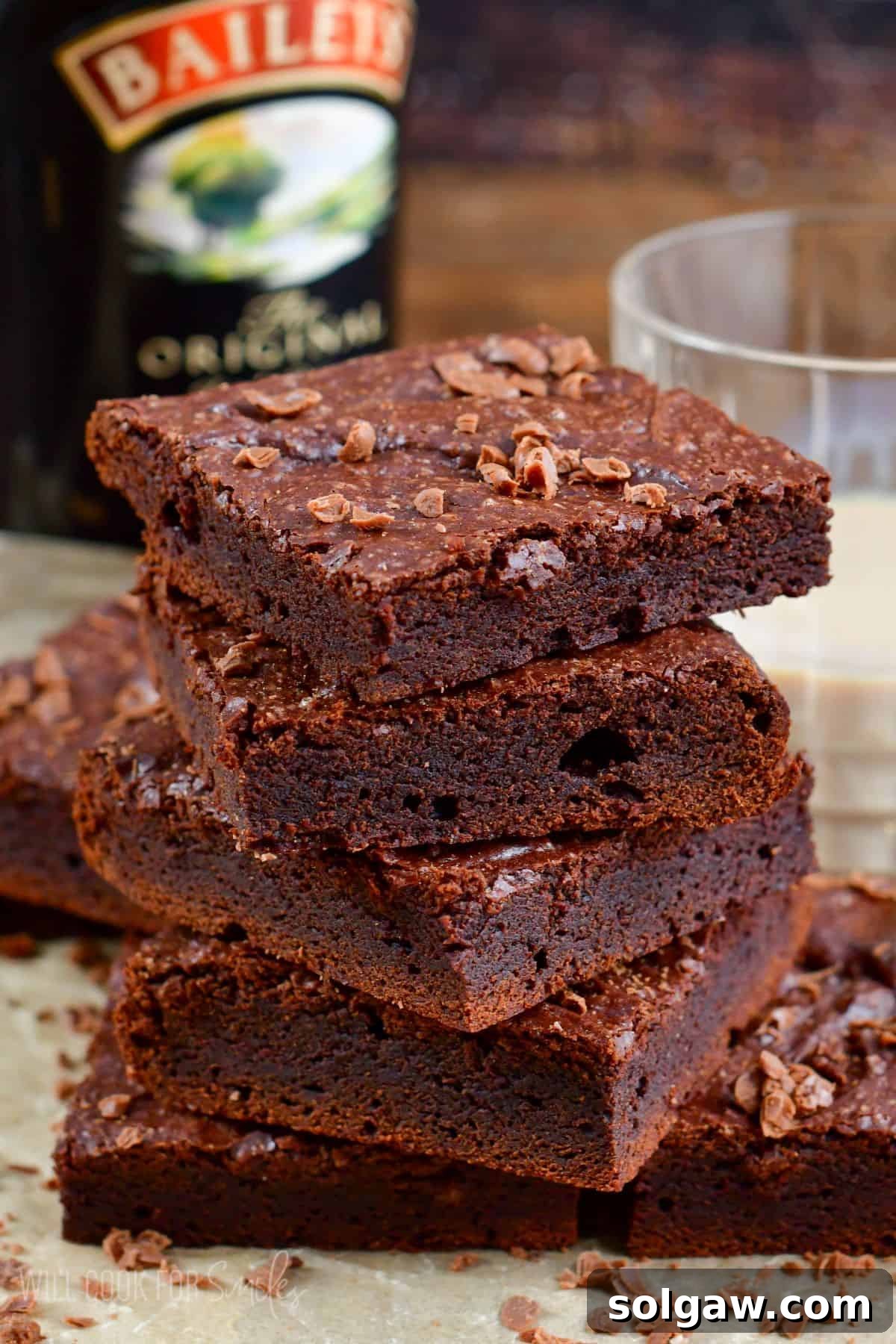Brownies cut into squares and stacked on up on a piece of parchment.