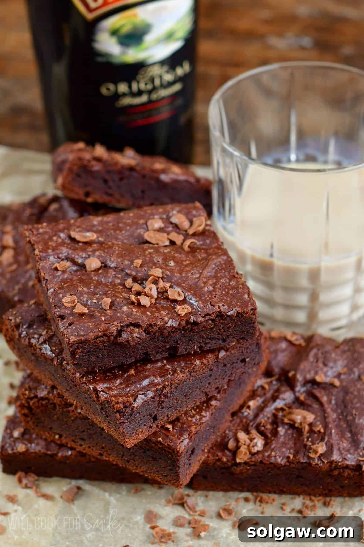 Baileys brownies stacked on a piece of parchment with chocolate shavings on top.