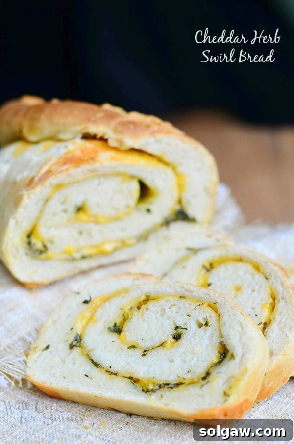 Golden brown Cheddar Herb Swirl Bread loaf, sliced, revealing the cheese and herb swirls, served on a wooden board.