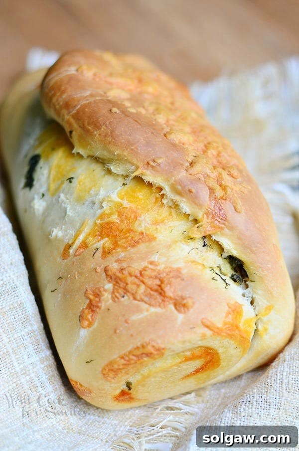 Four slices of Cheddar Herb Swirl Bread arranged on a white plate, showcasing the vibrant green herbs and melted cheese within the golden brown crust.