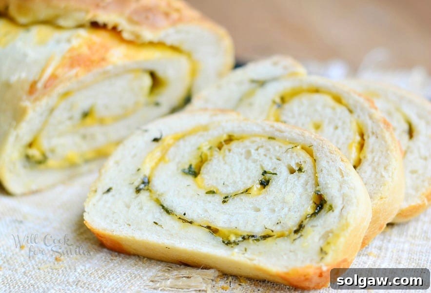 close up view of 2 slices of cheddar herb swirl bread on a brown placemat with the rest of the loaf behind in background