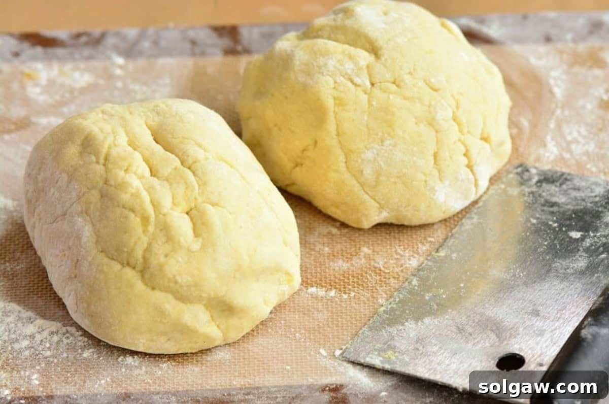 Pillowy Homemade Gnocchi Perfection 5 Gnocchi dough divided into two equal parts on a floured mat with a pastry cutter nearby.