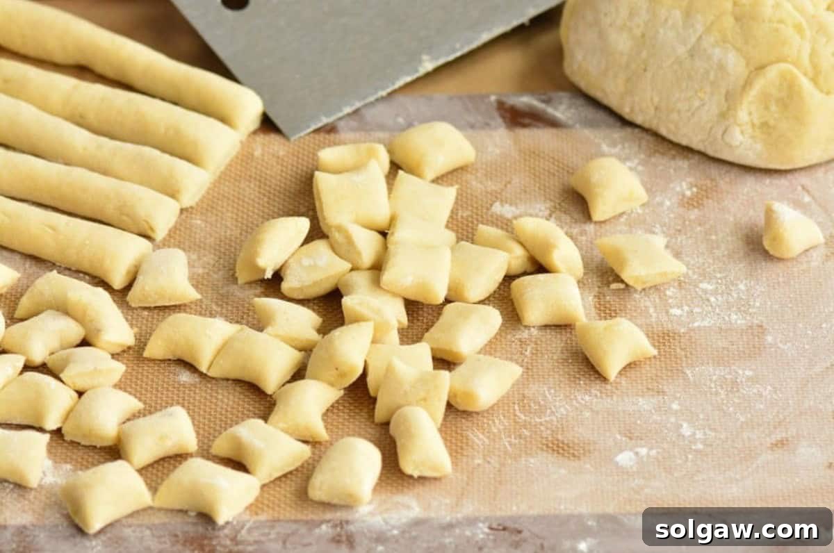 Pillowy Homemade Gnocchi Perfection 7 Cut strings of gnocchi dough shaped into individual pieces on a floured surface.