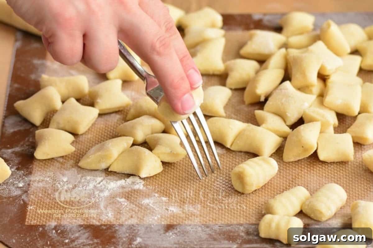 Pillowy Homemade Gnocchi Perfection 8 Rolling individual pieces of gnocchi on the tines of a fork to create ridges.